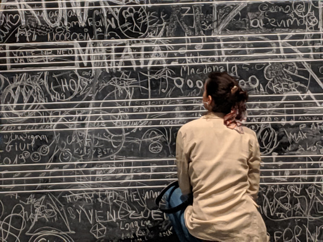 Woman writing on chalkboard with music staff